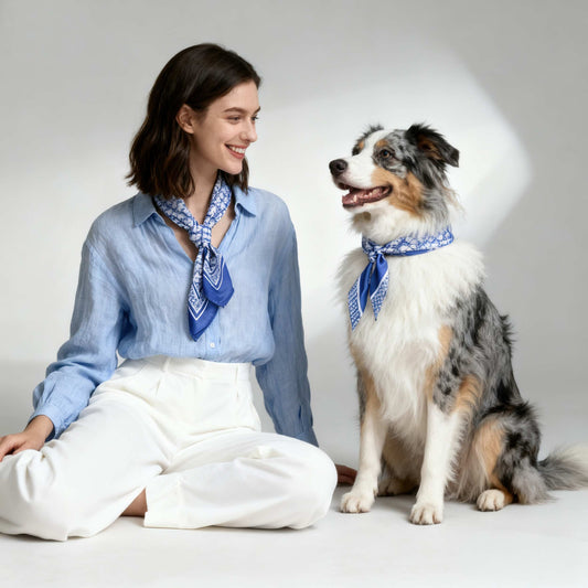 Woman and dog wearing matching blue bandanas on a white background
