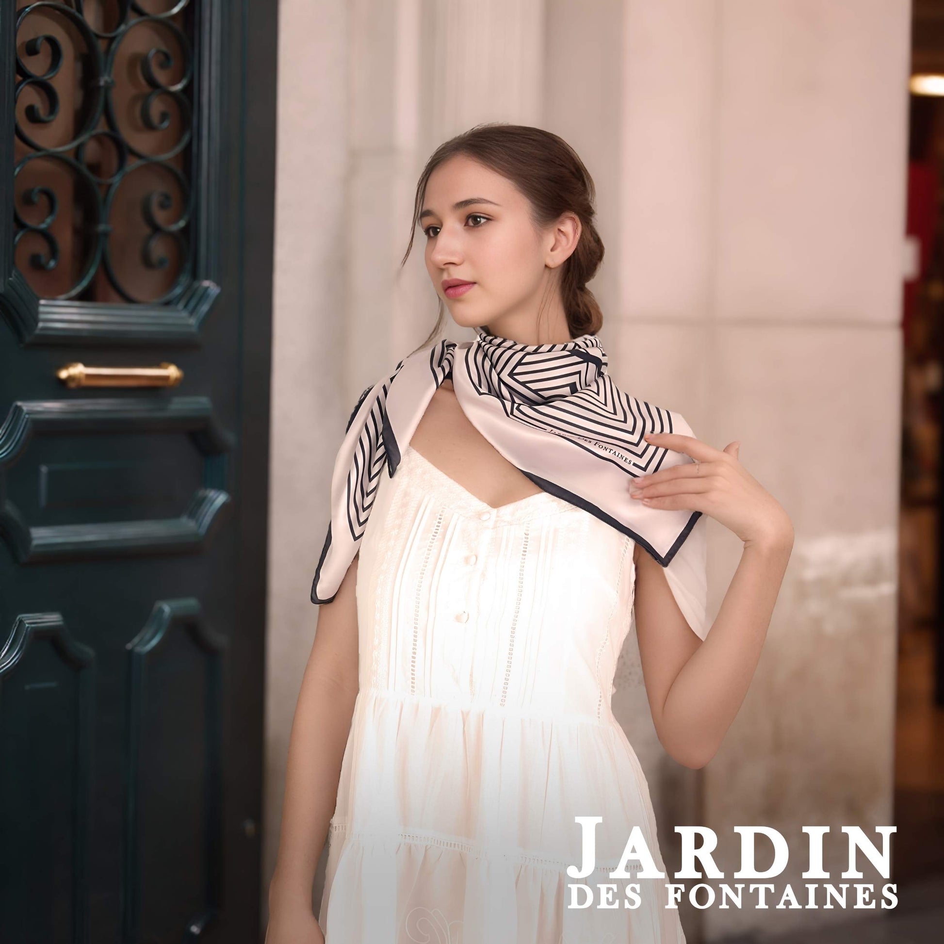 Woman wearing a black and white patterned scarf, standing in front of a decorative door.