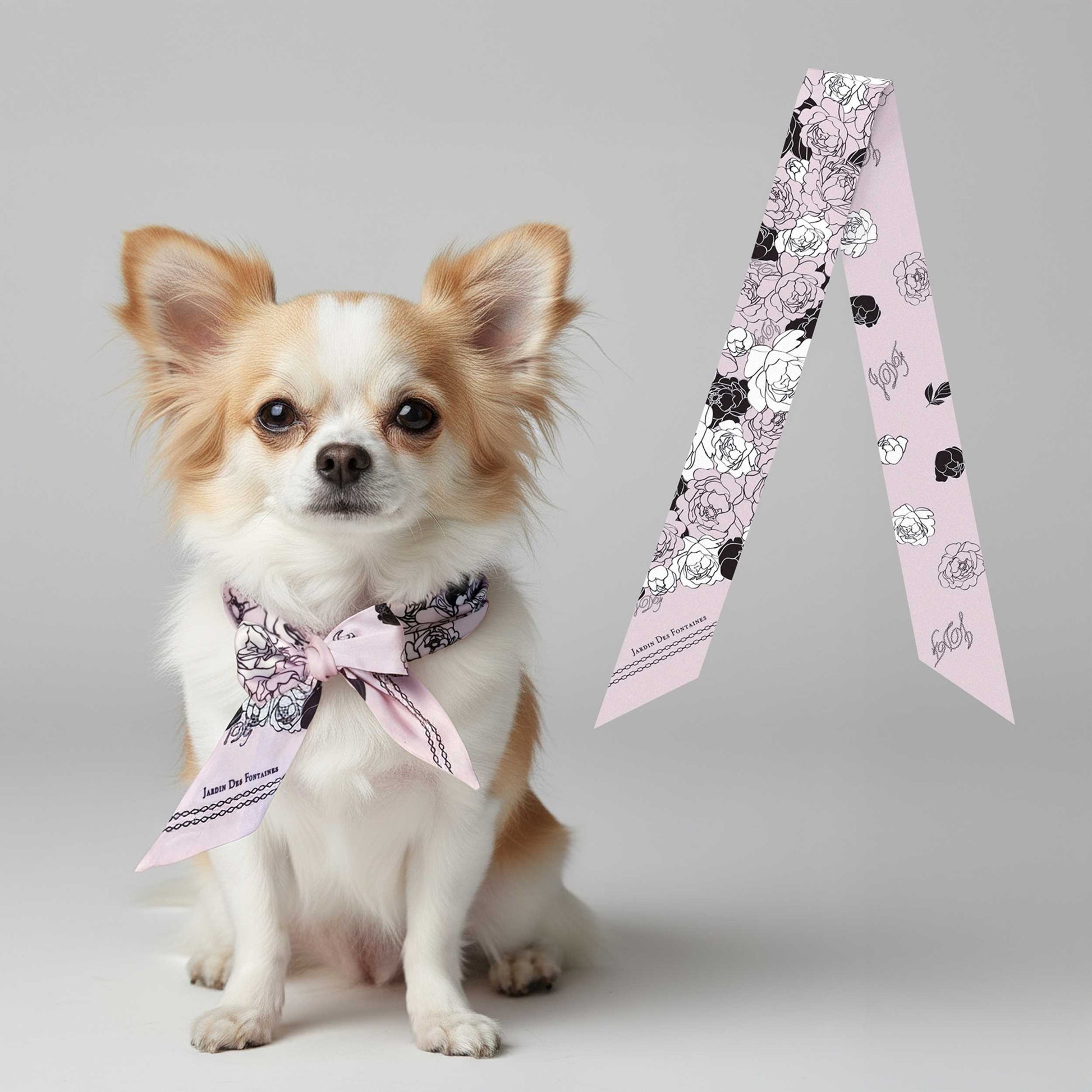Small dog wearing a floral bow tie with a matching scarf on a gray background